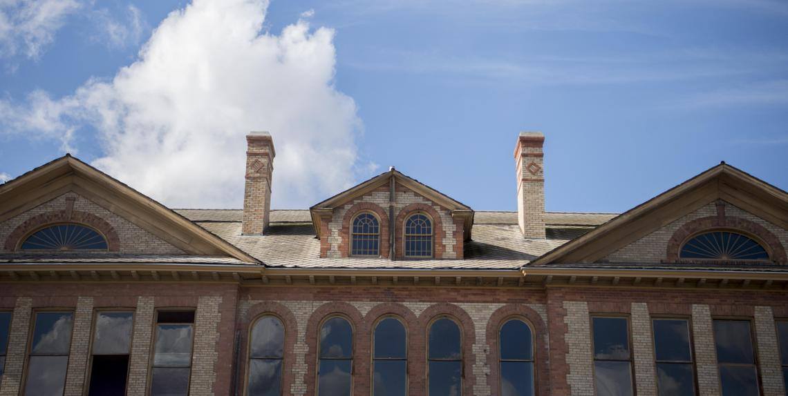 An outdoor photograph of a building with brick design work and large glass windows.